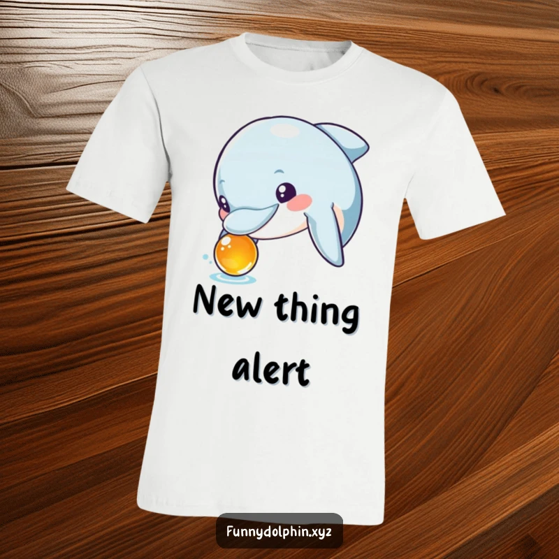 Funny T-shirt featuring a curious dolphin with wide, excited eyes examining a shiny, unknown object. A true explorer!